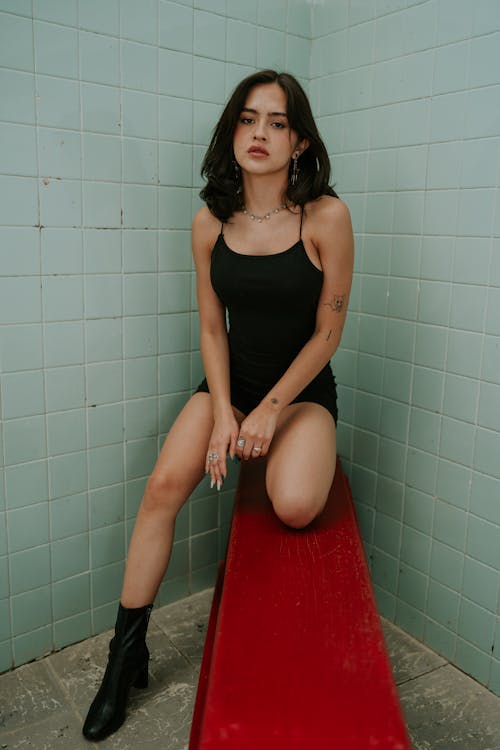 Young Woman in Black Clothing and Boots Posing on a Red Bench 