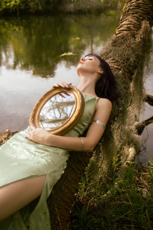 Free Woman in Dress Lying Down with Mirror on Tree Stock Photo