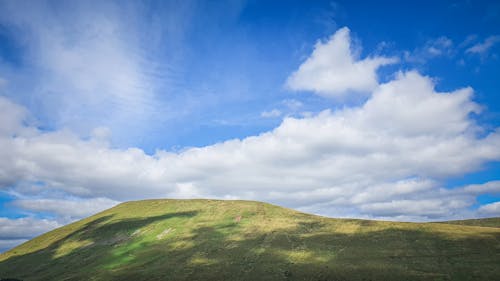 A grassy hill with clouds in the sky
