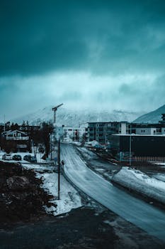 挪威特隆斯特一条安静的街道上，冬日场景显得喜怒无常，天空阴沉，雪花飘落