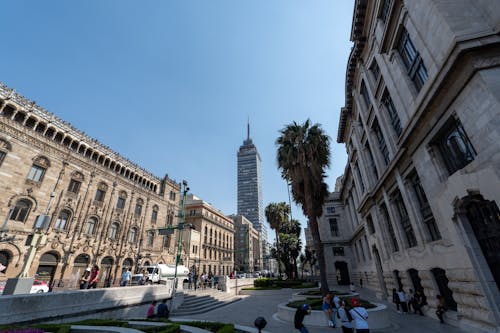 A city square with people walking around and a tall building