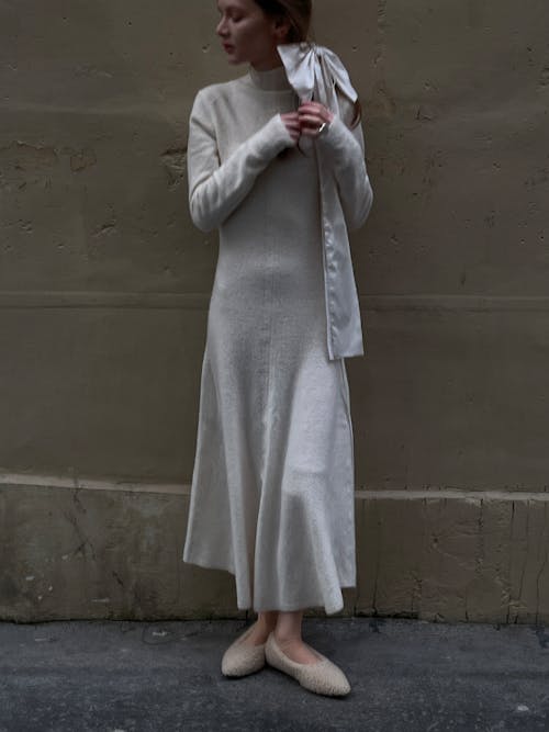 A woman in a white sweater dress and white shoes