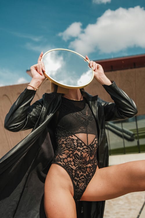 Woman in Leather Coat and Lingerie Holding Mirror
