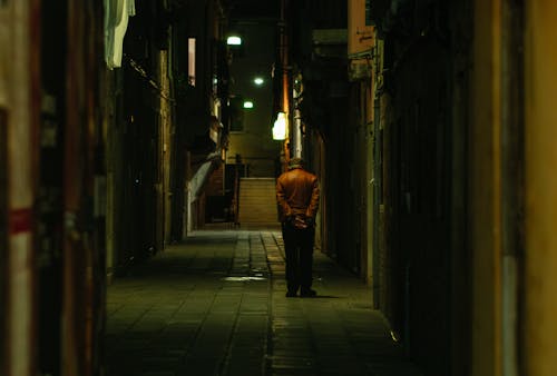 A man is walking down a dark alley at night