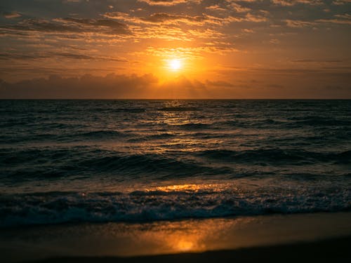 the sun is rising over the ocean beach