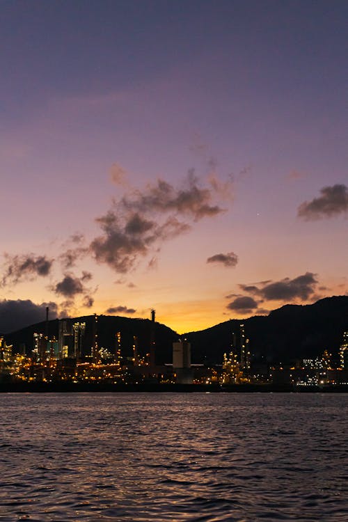 A city skyline with a large refinery in the distance