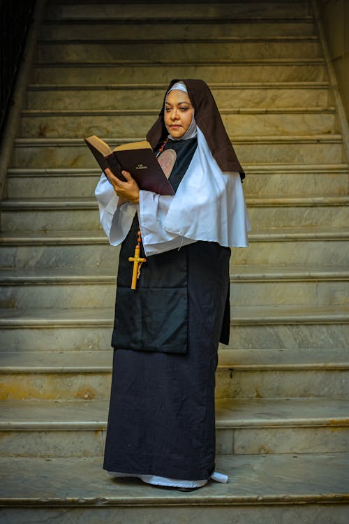 A nun is reading a book on the steps