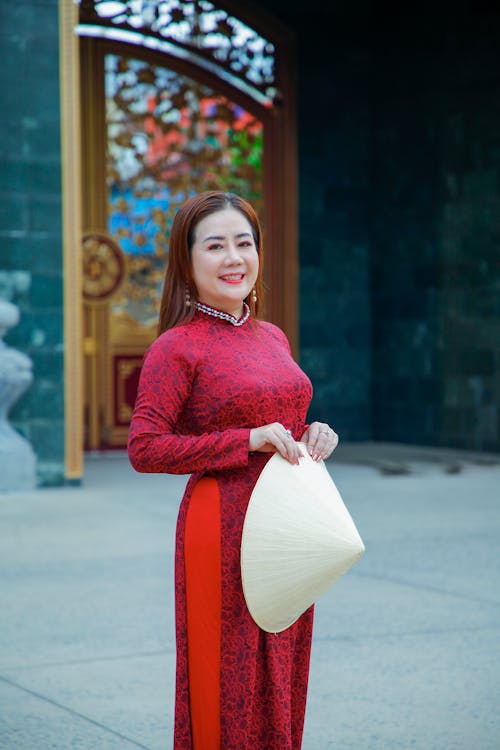 A woman in a red and white dress holding a white hat