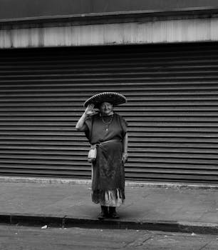 城市街道上，一位穿着传统服装的老年妇女的黑白肖像