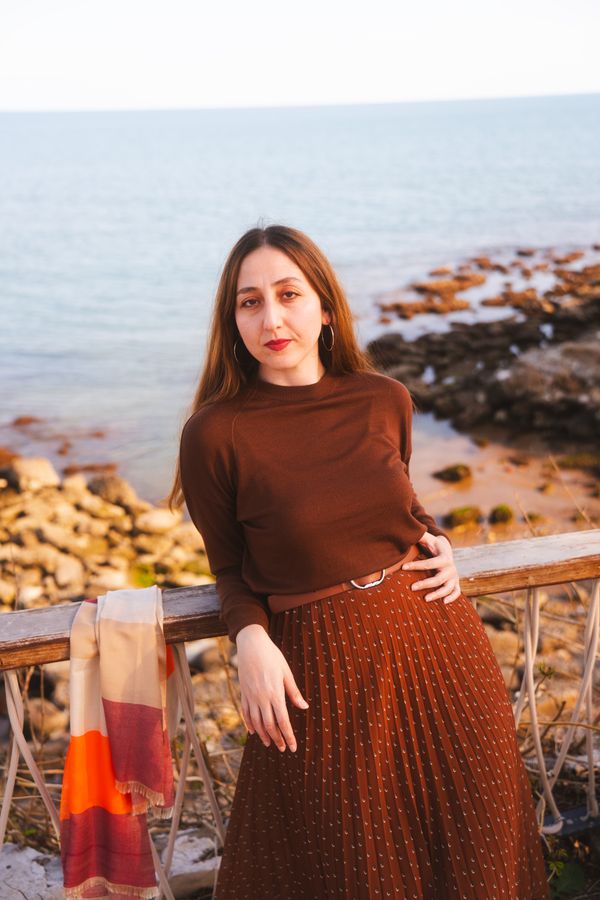 Woman wearing a mock-neck knit with a pleated midi skirt
