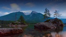 在布满星星的黄昏天空下，湖面与山和树显得格外宁静