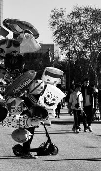Black and white photo of a street vendor selling cartoon balloons in Barcelona. Urban life captured.