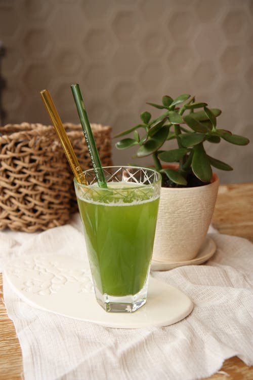 A green drink with straws and a plant