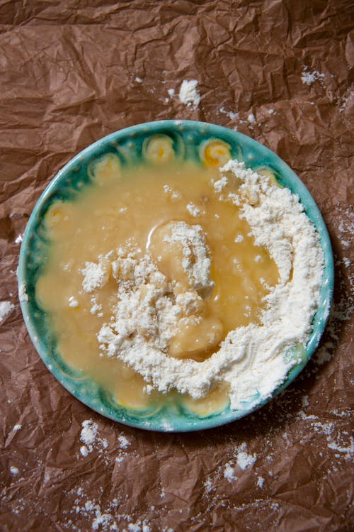 A plate with a bowl of flour and a spoon