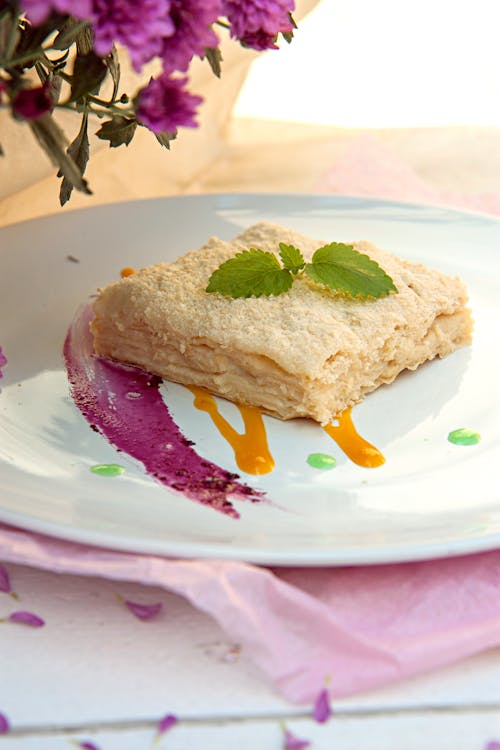 A dessert on a white plate with purple flowers