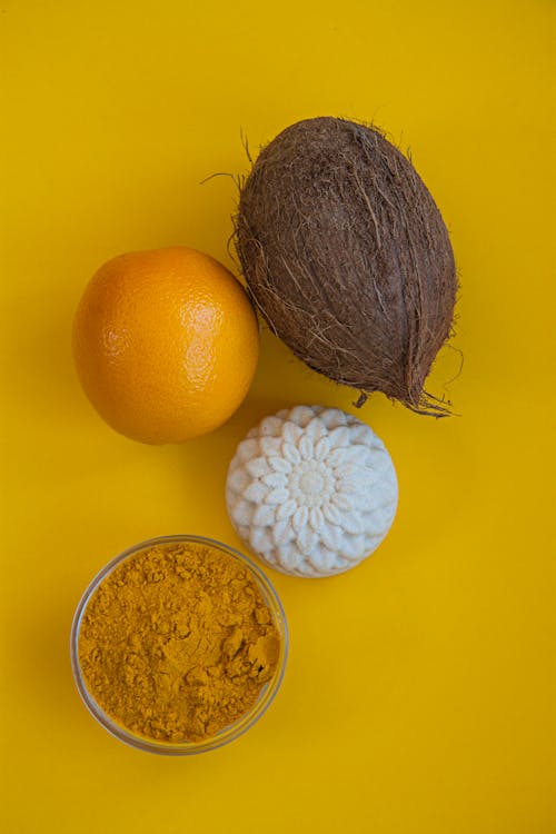 Tumeric, coconut oil, and orange on a yellow background