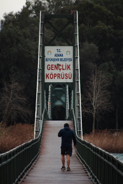 A man walking across a bridge with a sign that says genkop