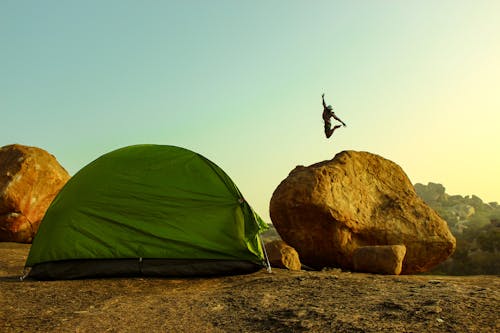 Rock tent and climber in sunny morning in hampi