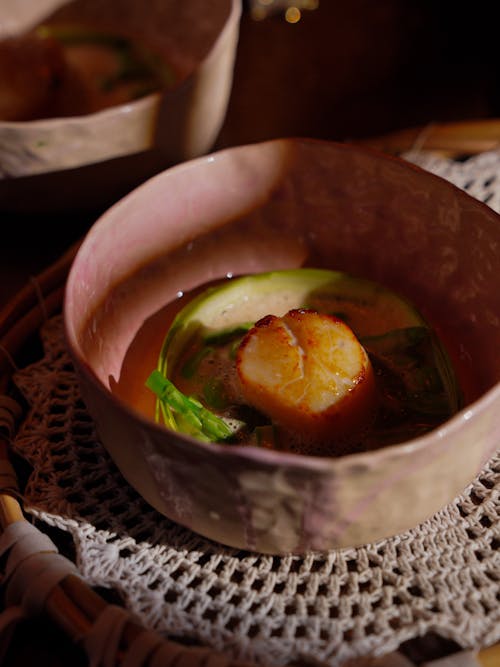 A bowl of food with scallops and a spoon