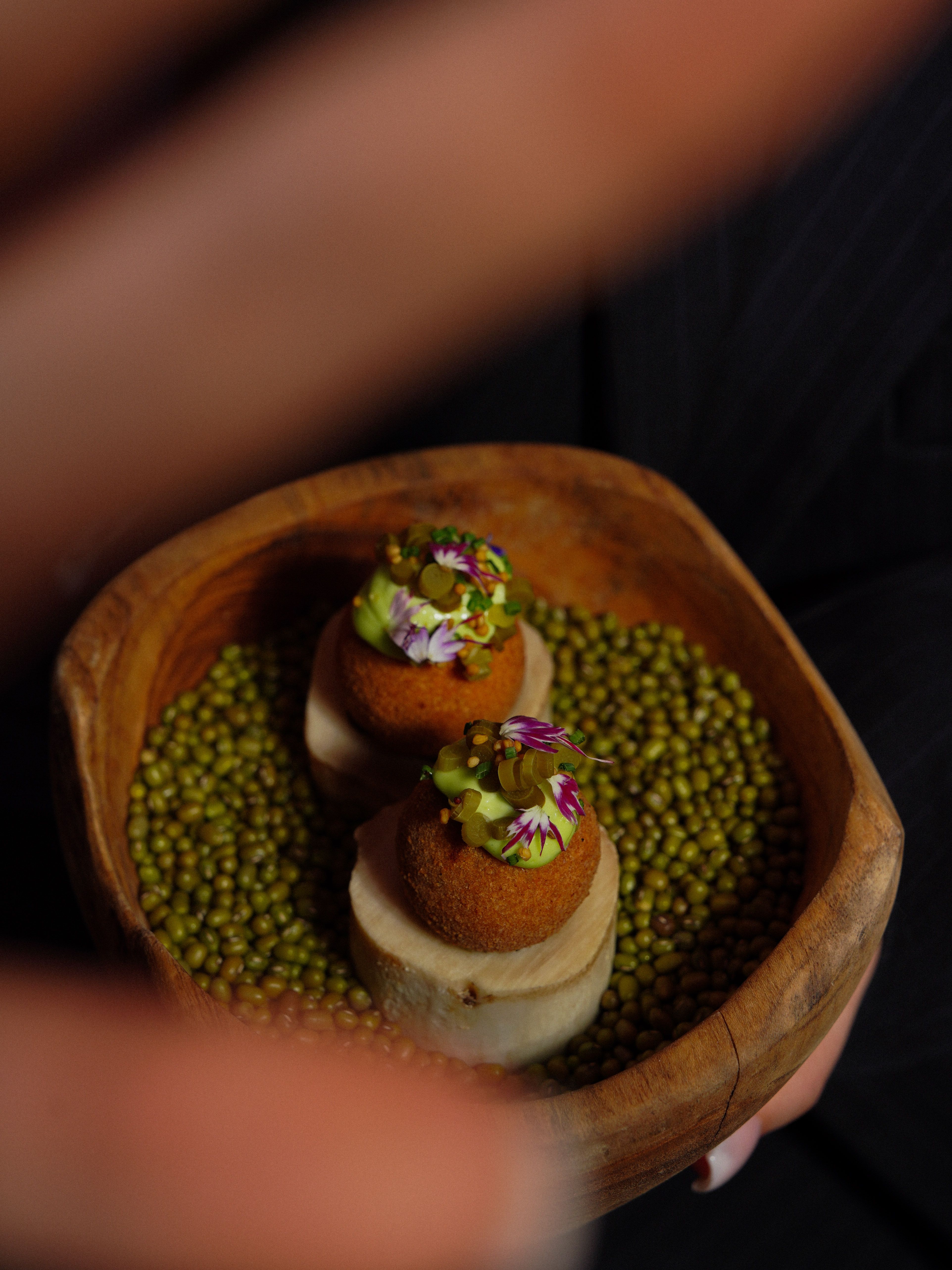 Elegant gourmet fried snacks served in a wooden bowl with green peas.