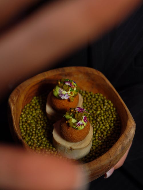 A person holding a wooden bowl with food on it