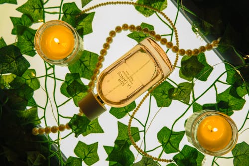 A bottle of perfume with candles and leaves