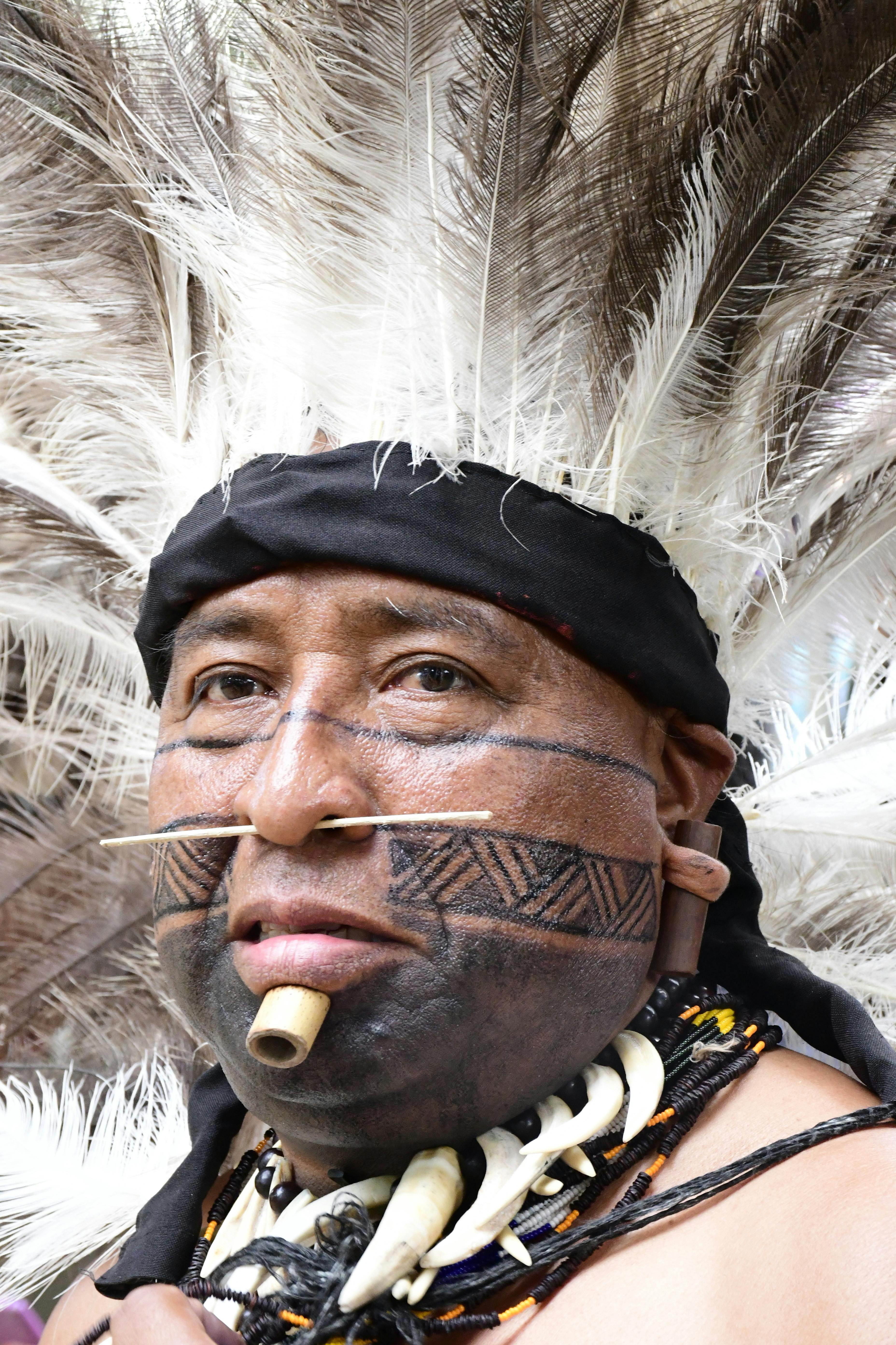 man in plume and with tattoo and piercing on face