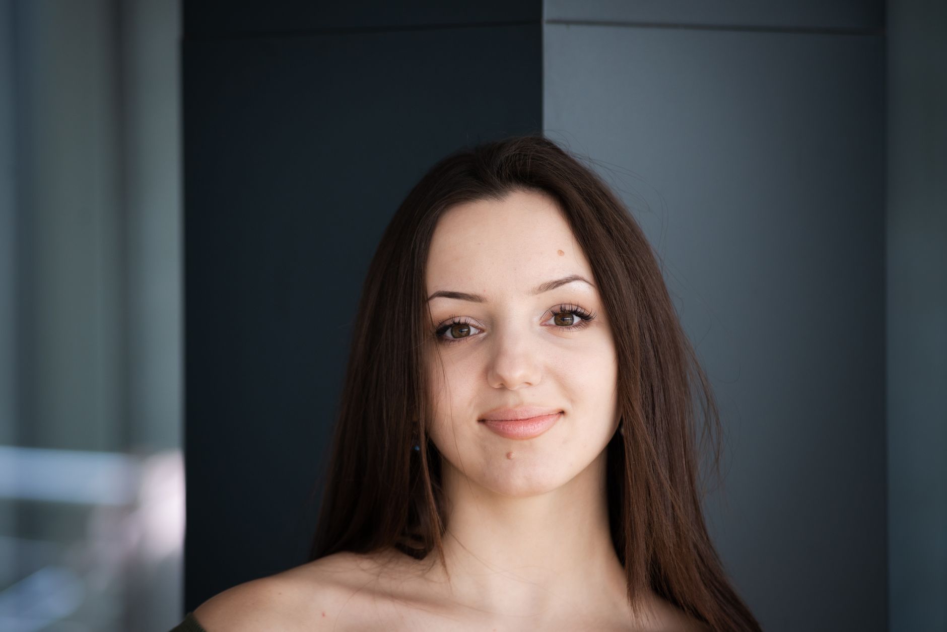 A close-up portrait capturing a young woman smiling warmly, with natural light enhancing her features.
