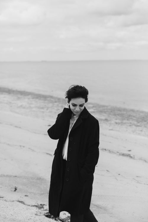 Free Elegant black and white portrait of woman on beach in winter coat. Stock Photo