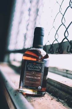 A bottle of rich amber Crown maple syrup positioned beside a rustic window, radiating warmth.