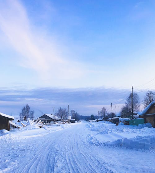 A snowy road with a small village in the background