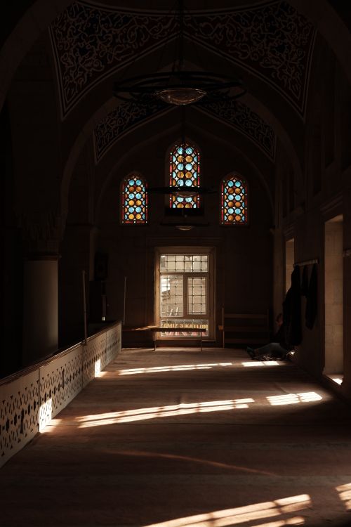 Free A sunlit church aisle featuring beautiful stained glass windows casting colored light inside. Stock Photo