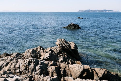 Free Stunning rocky seashore in Gamagori, Japan with clear blue ocean and distant islands. Stock Photo