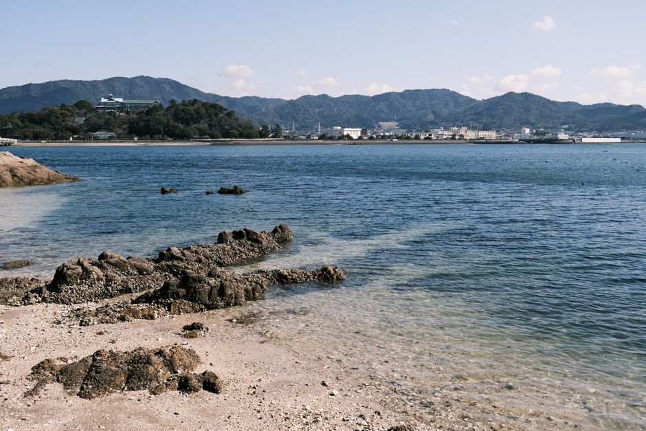 Serene seaside landscape of Gamagōri with lush hills and calm waters.