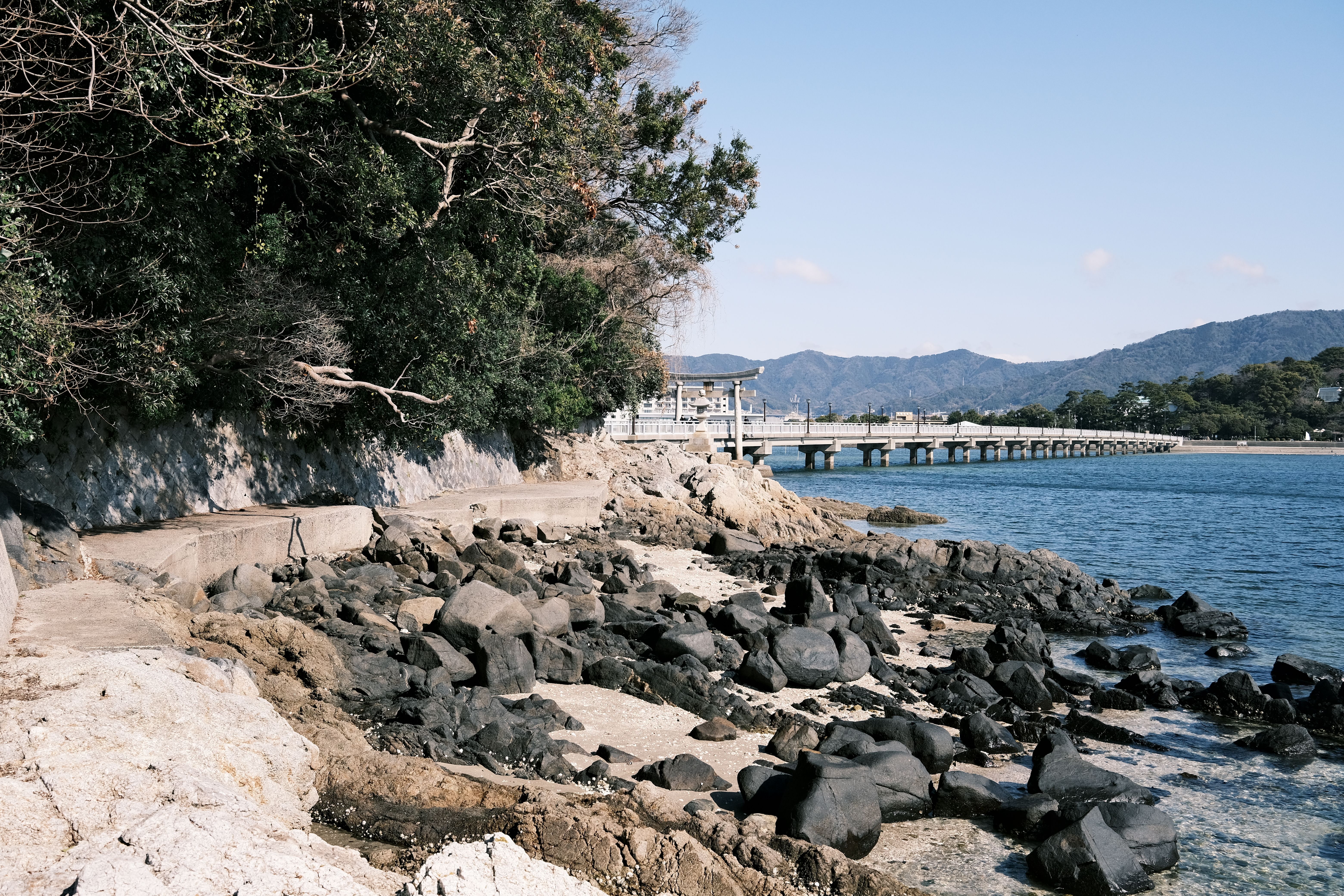 Explore the picturesque rocky beach and serene pier in Gamagōri, Aichi, Japan.