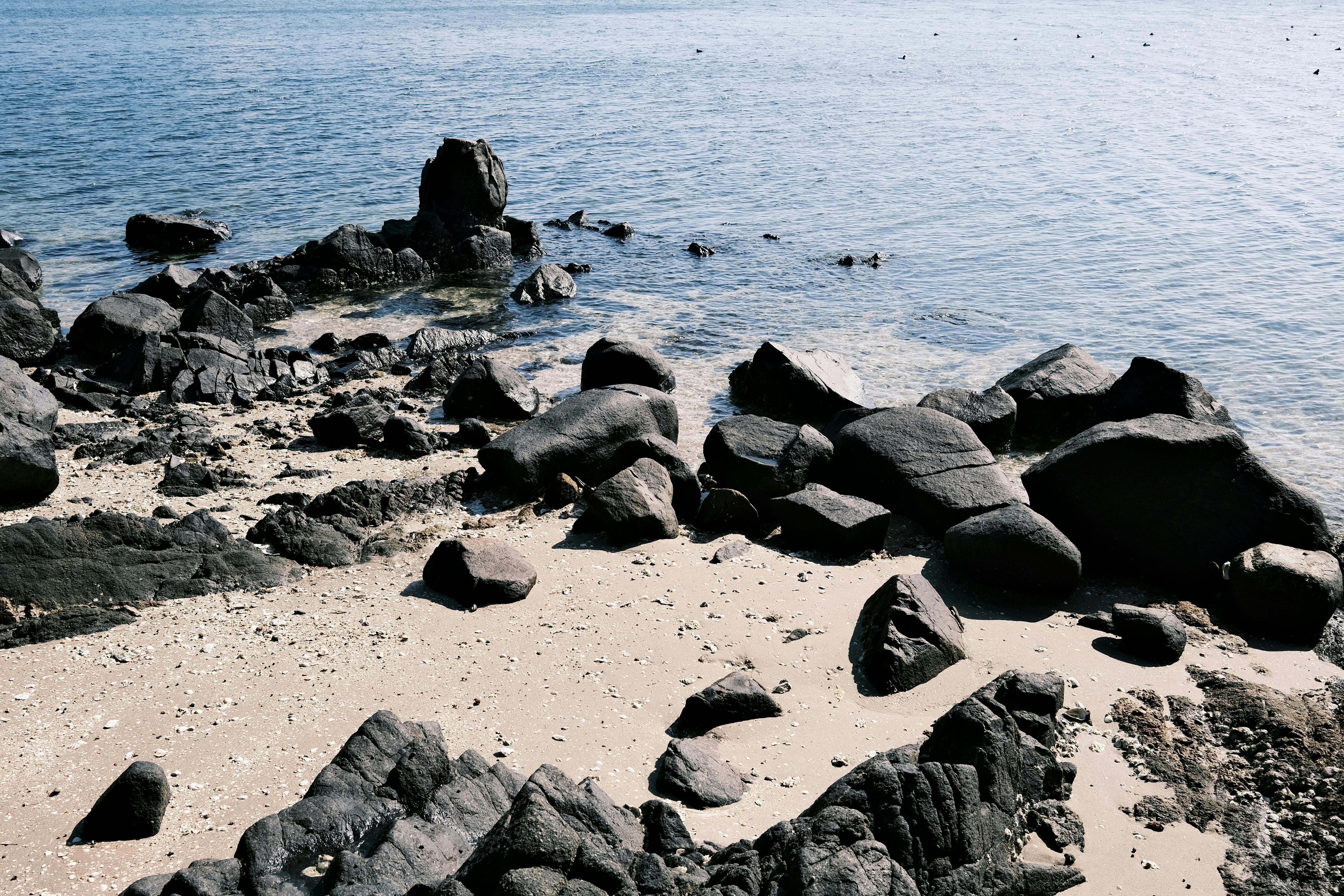 Coastal rocks and sandy shore in Gamagōri, Aichi, capturing tranquil seascape.