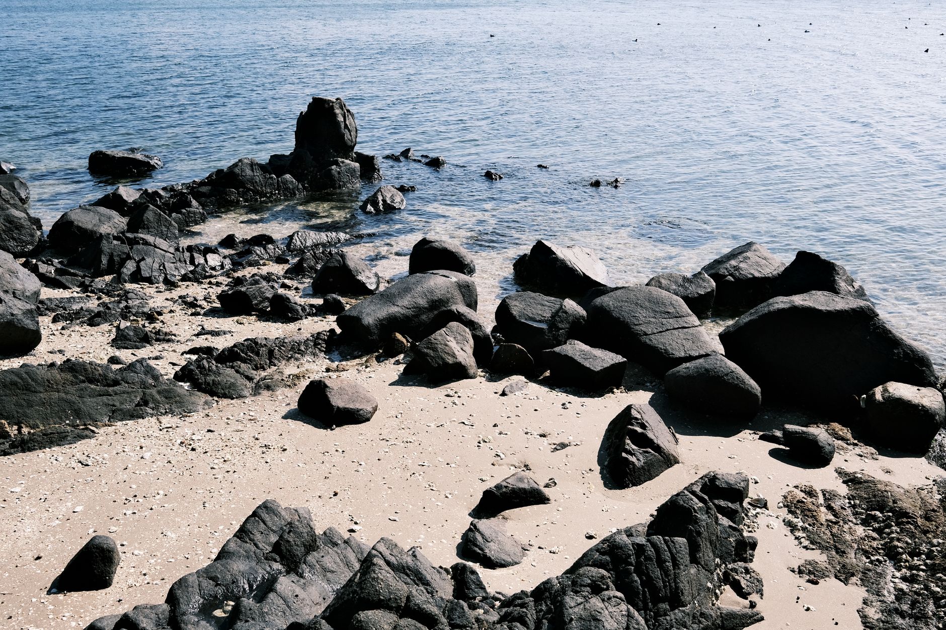 Coastal rocks and sandy shore in Gamagōri, Aichi, capturing tranquil seascape.