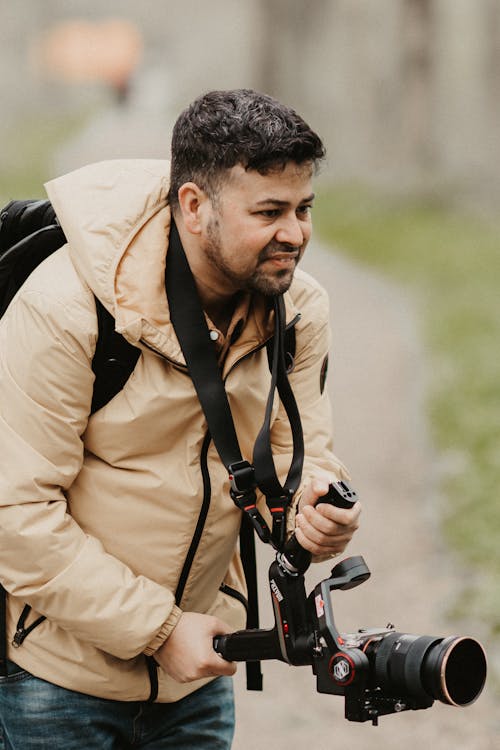 A man with a camera and backpack walking down a path