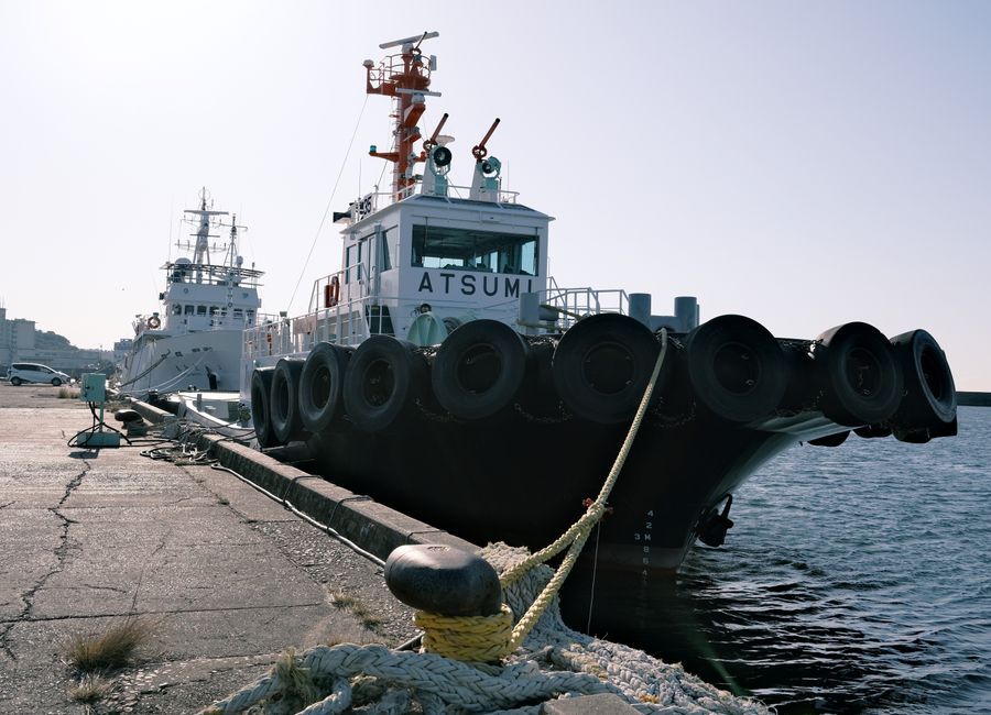 Two moored tug boats at the Gamagōri Harbor, Aichi, Japan, under bright sunlight.