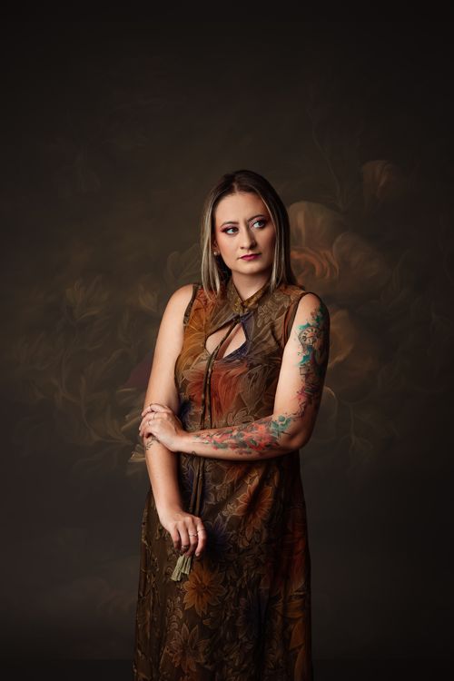 Free Elegant young woman with tattoos posing in a studio portrait with floral background. Stock Photo