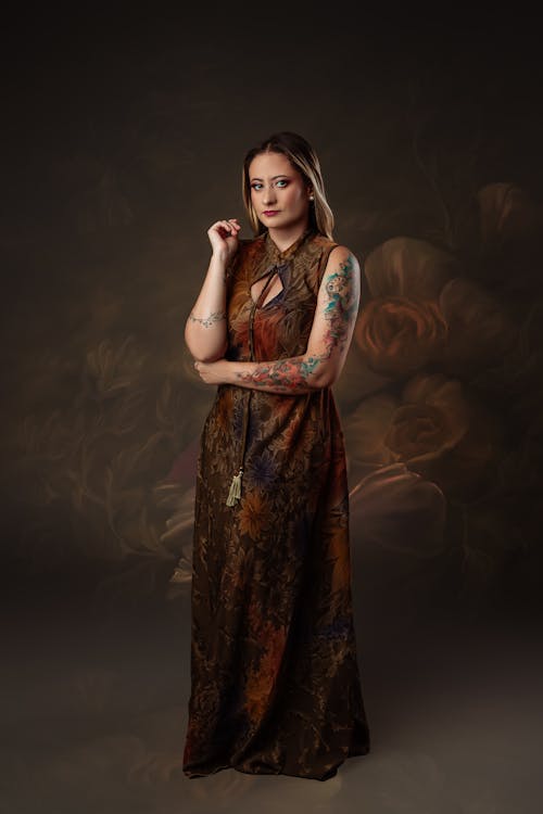 A woman with tattoos posing in a long dress
