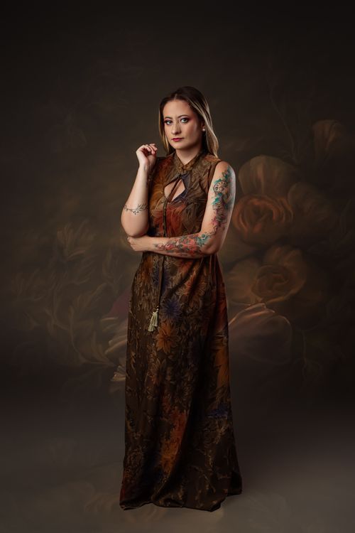 Free Elegant woman with tattoos in a floral dress posing in a studio setting. Stock Photo