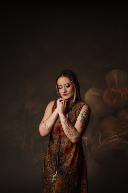 A woman in a dress with tattoos on her arms