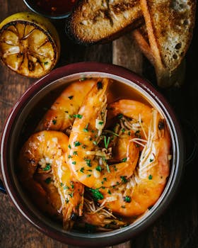 Delicious gourmet shrimp in sauce served with grilled lemon and crispy bread.