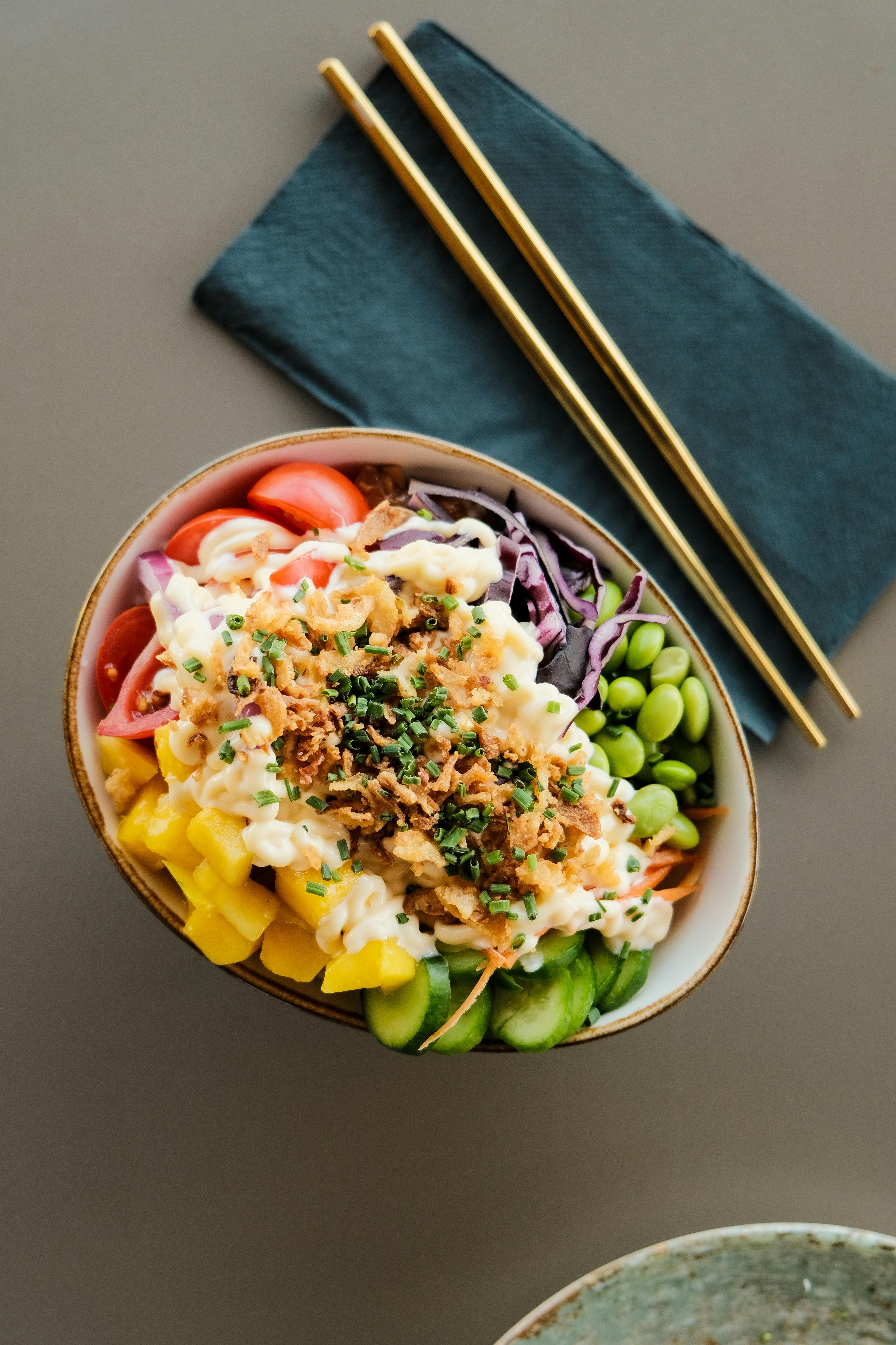 A vibrant overhead shot of a fresh salad bowl with various vegetables and chopsticks on the side.