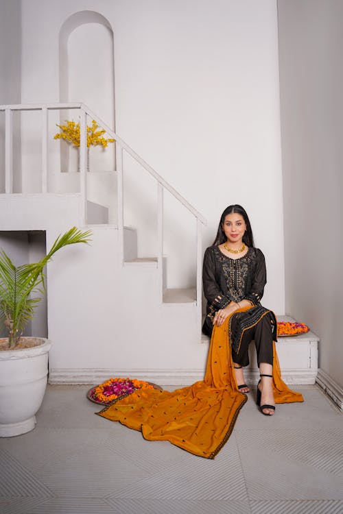 A woman in black and orange sitting on stairs