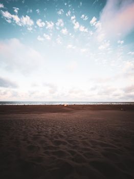 A peaceful beach scene showcasing the ocean and sky under a blanket of clouds, creating a tranquil summer vibe.