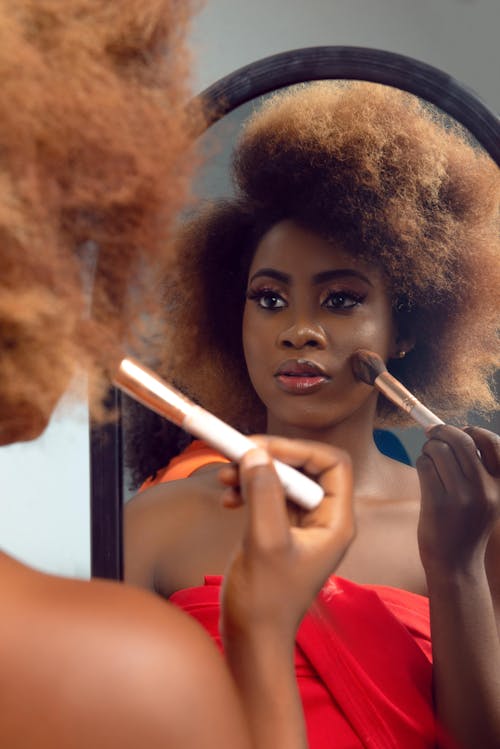 A woman with afro hair is looking in the mirror