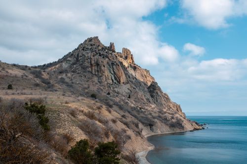 Free Stunning view of a rocky coastal cliff under a cloudy blue sky. Stock Photo