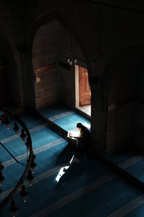 Free Man Sitting in Darkness at Mosque Stock Photo